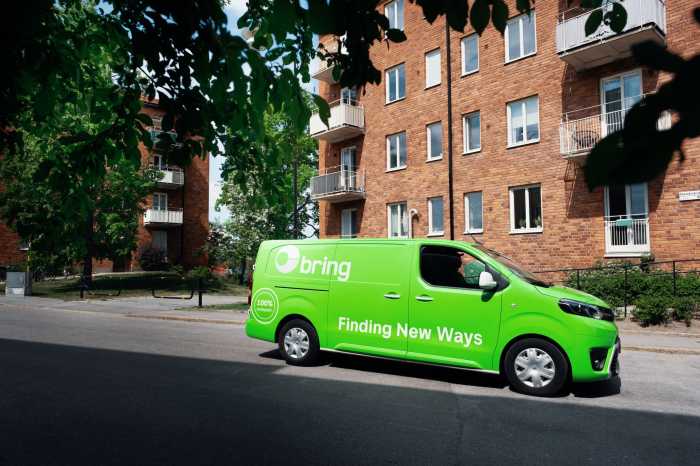 En Bring budbil står vid ett höghus