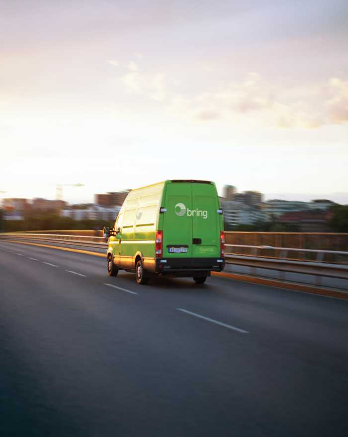 Budbil kör på bro i solen