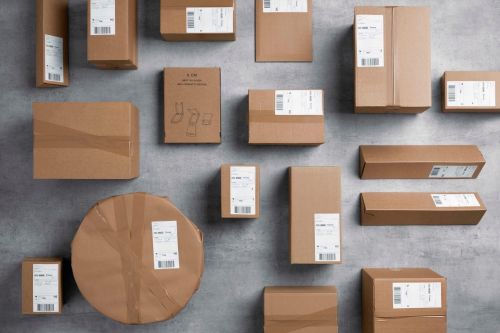 Många emballerade bruna paket i olika storlekar och former som ligger på en plan grå yta