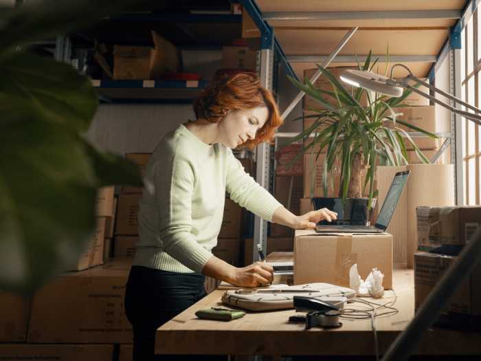 Kvinna står på lager med laptop