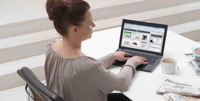 En kvinna sitter vid datorn med en kopp kaffe