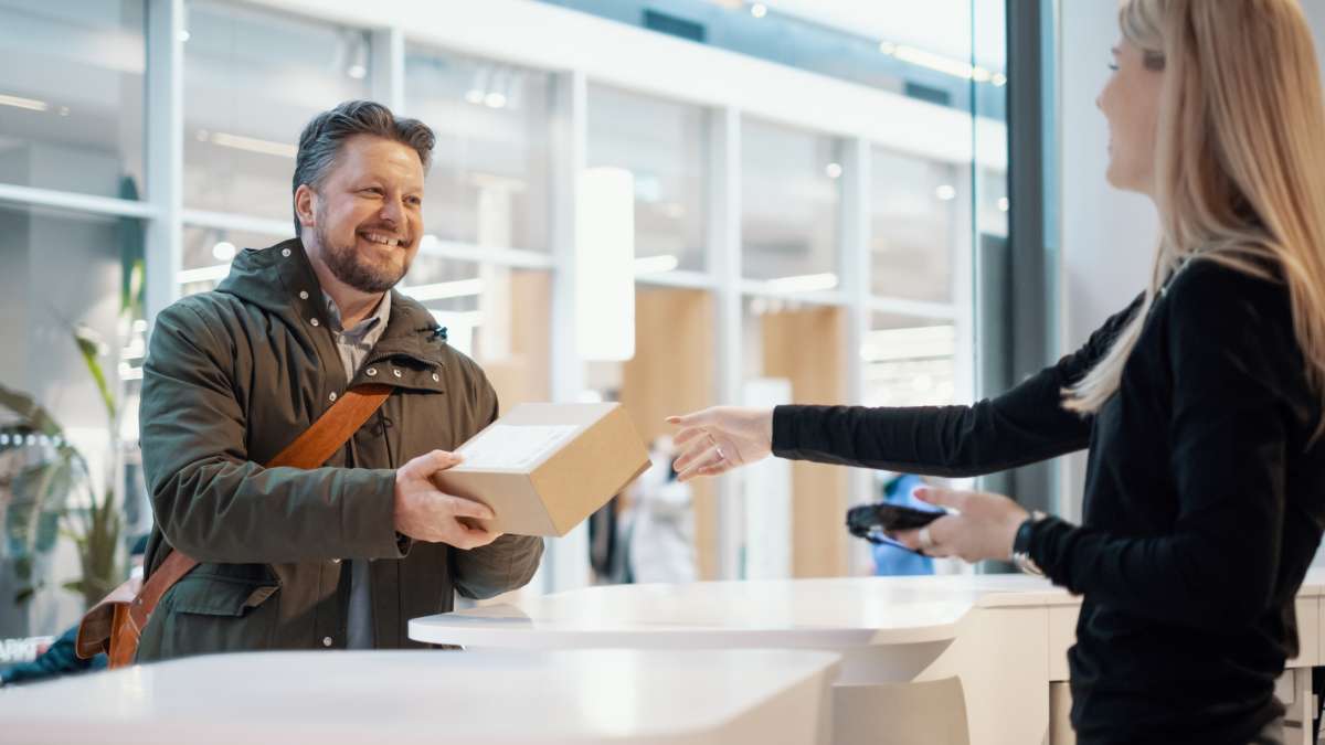 Man står vid en expeditionsdisk och hämtar ut ett paket som han köpt i en nätbutik