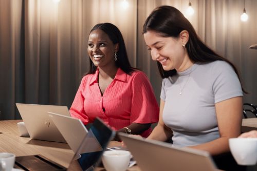 Två kvinnor arbetar på sina datorer.