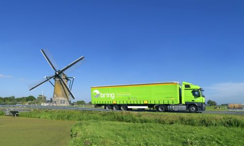 Bring lastbil passerar en väderkvarn längs vägen