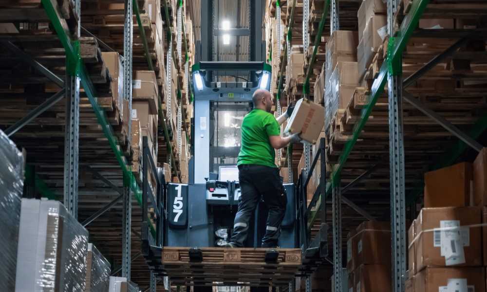 Man hämtar paket på ett lager ståendes på en truck